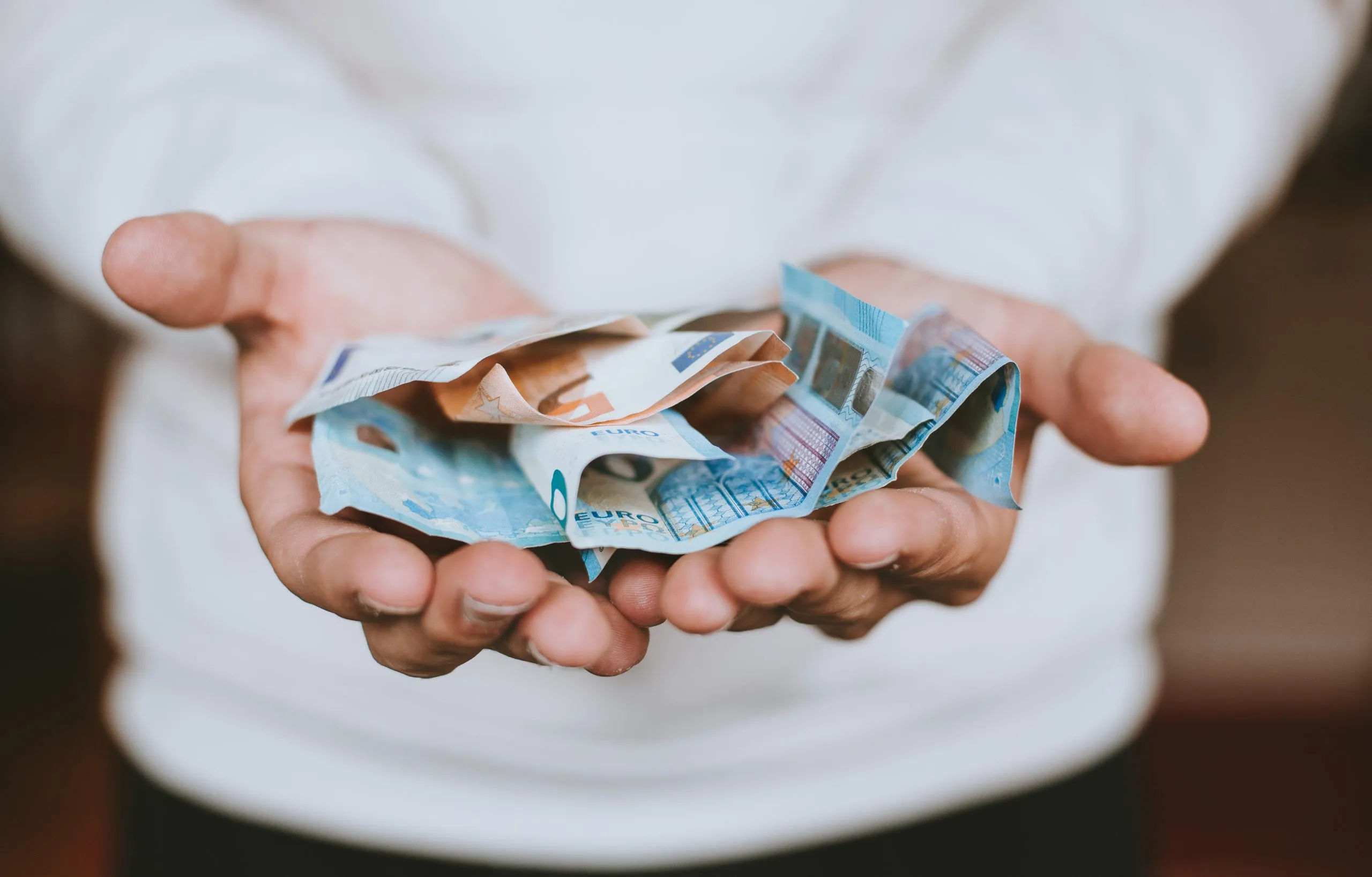 Hände halten Euro-Scheine. © Christian Dubovan on unsplash